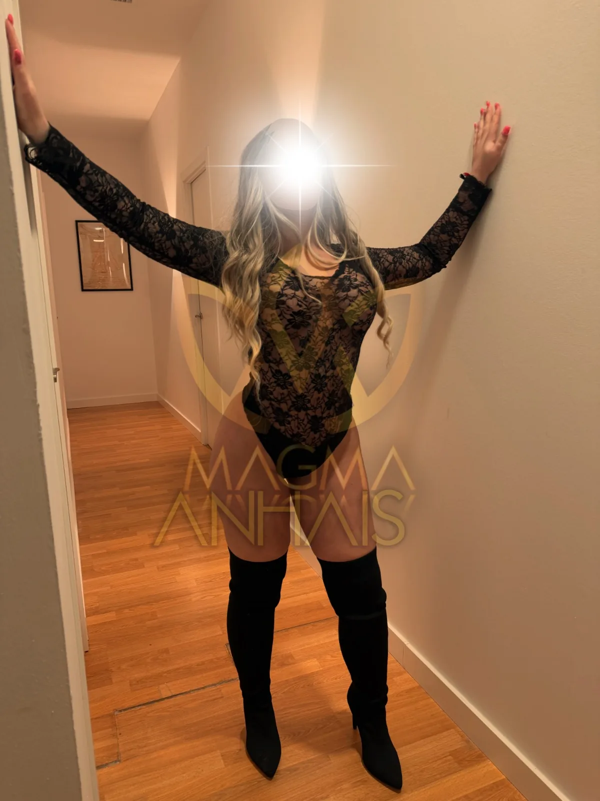 Anhais in a long-sleeved black bodysuit and high boots, reaching towards the corridor walls.