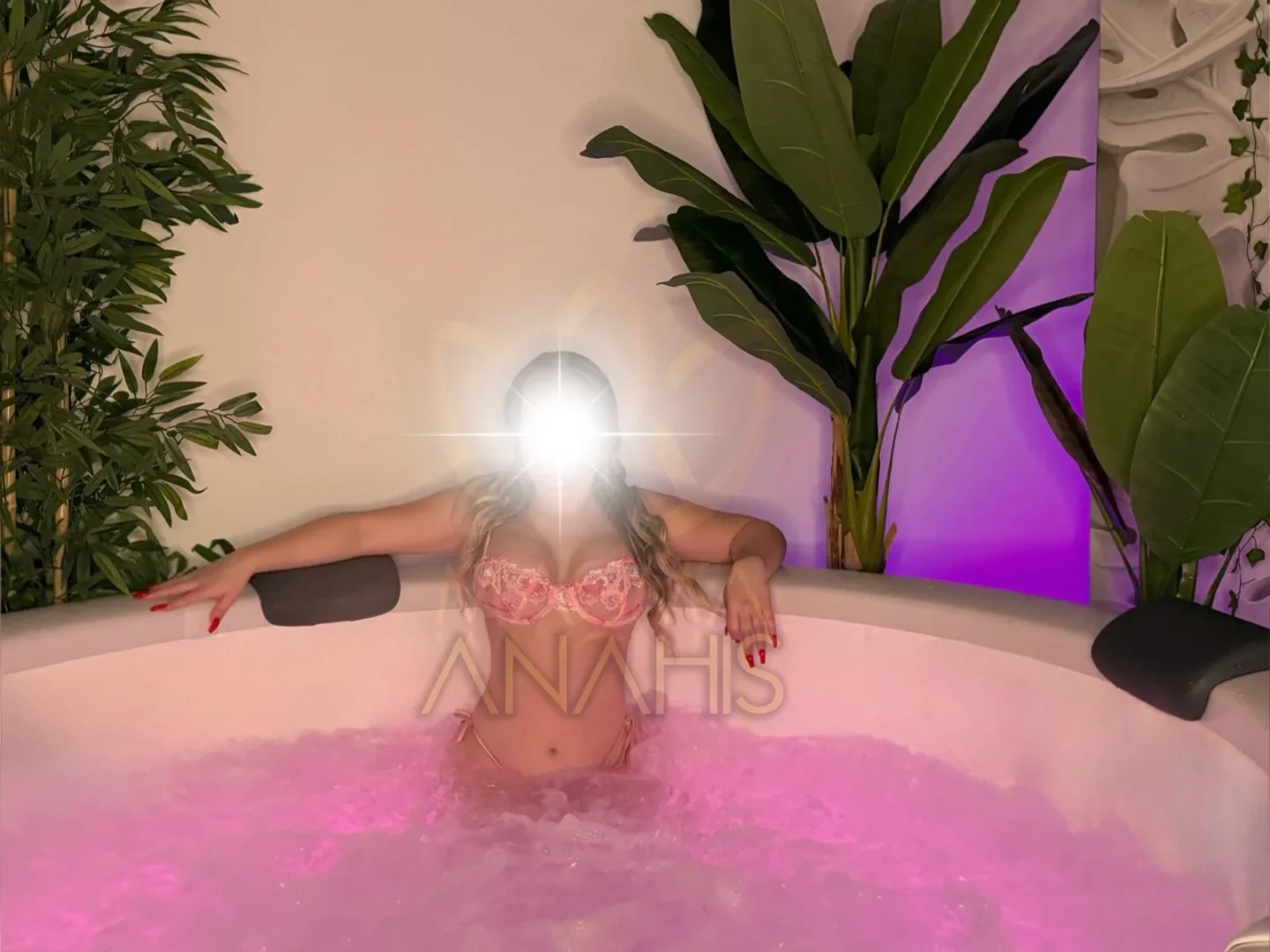 Wide view of Anhais seen from behind in the whirlpool bath, surrounded by plants and the bath edge.
