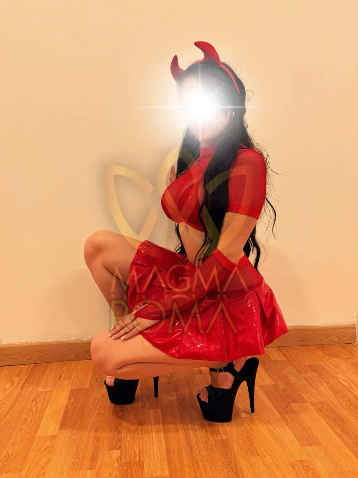 Roma in a red outfit, headband and black platform shoes in a white corridor.